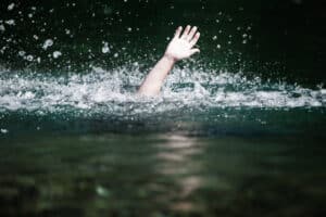 A man who's drowning, waving his hand above the water to ask for help.
