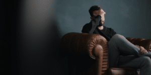 Picture of a man holding his head in his hand.