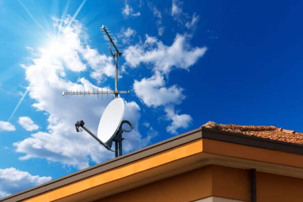 Satellite dish and TV antennas on the house roof with a beautiful blue sky