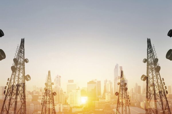 Silhouette, telecommunication towers with TV antennas and satellite dish in sunset, with double exposure city in sunrise background