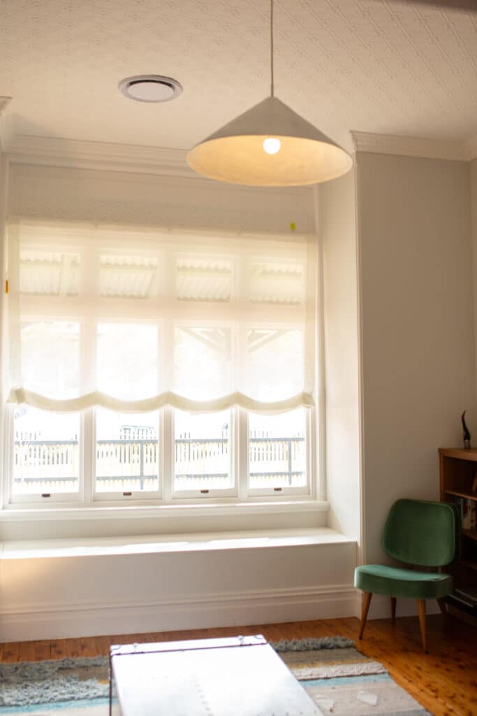 soft roman blinds in linen look fabric for window in wagga wagga with upholstered arm chair.
