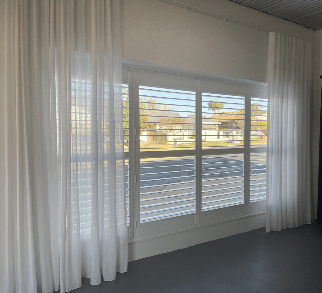 white plantation shutters installed in a window with bespoke custom sheer curtains over the top by Riverina Interiors Wagga.